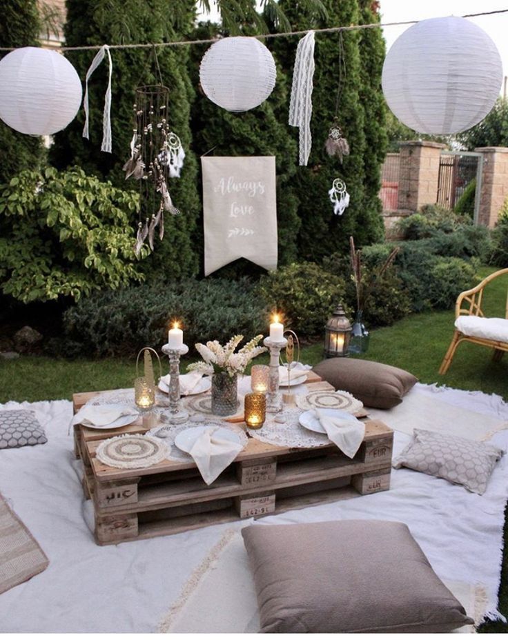 an outdoor table with candles and plates on it