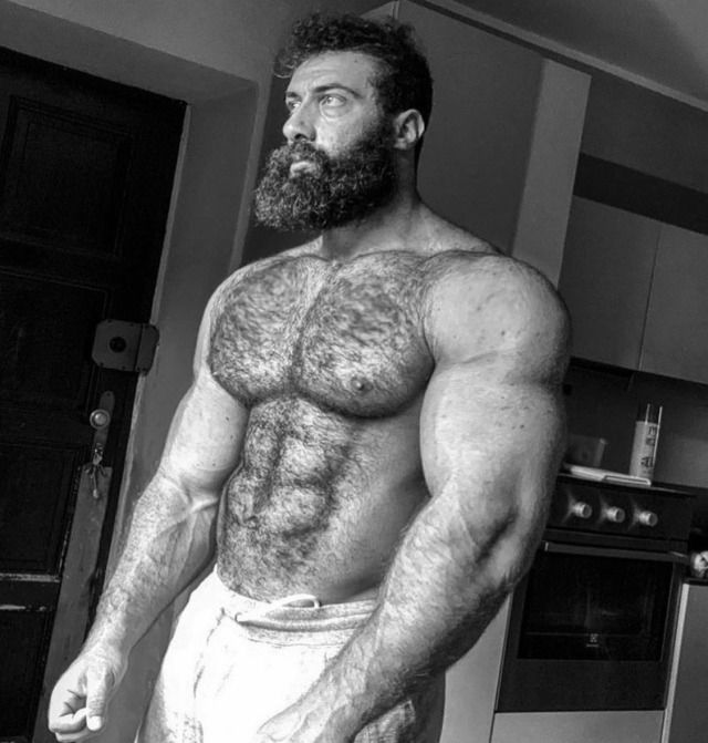 a man with a beard and no shirt standing in a kitchen