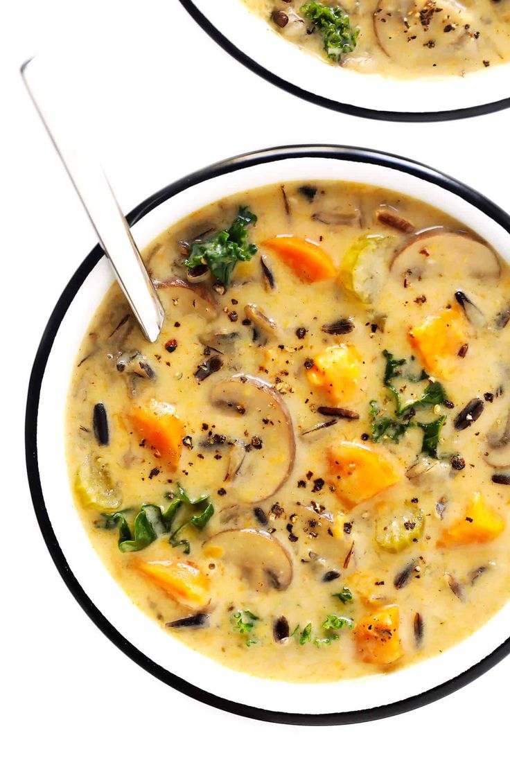 two bowls of soup with mushrooms, carrots and broccoli in it on a white background