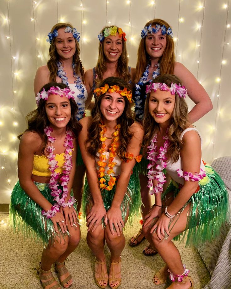 a group of women dressed in hula skirts and leis pose for a photo