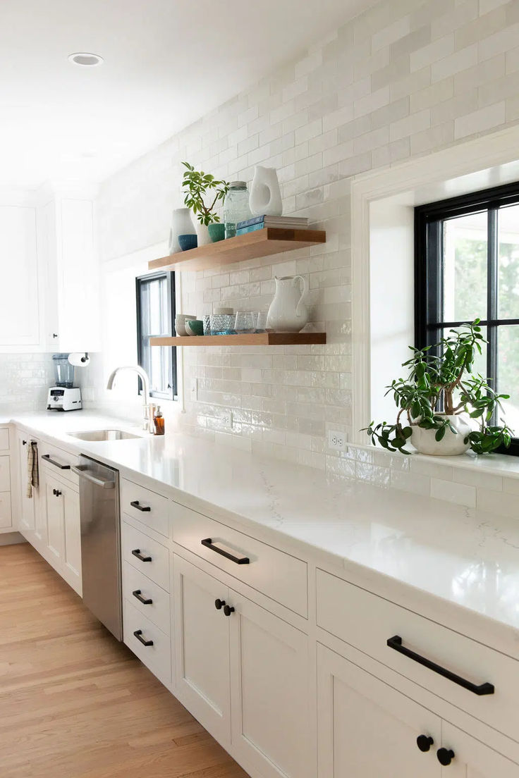 a kitchen with white cabinets and open shelving above the sink is seen in this image