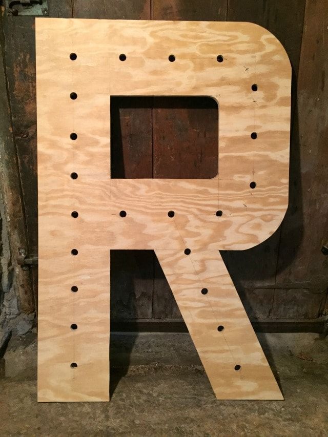 the letter p is made out of plywood and has holes in it to make letters