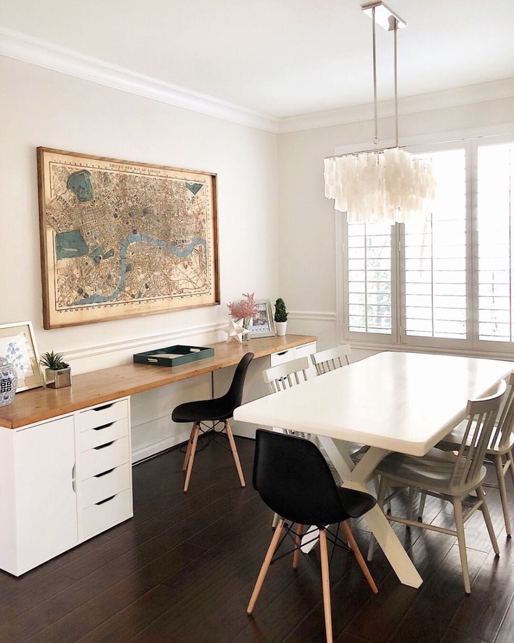 a dining room table with four chairs and a map hanging on the wall above it