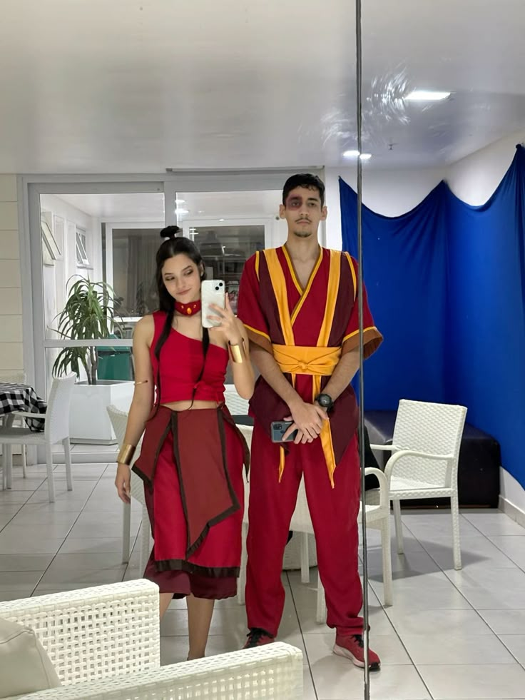 a man and woman in costume taking a selfie with a cell phone while standing next to each other