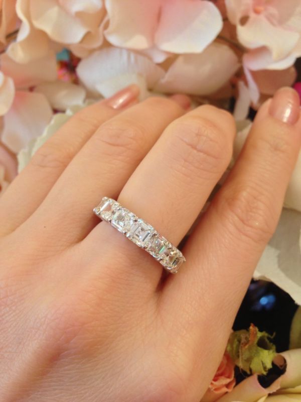 a woman's hand with a wedding ring on it and flowers in the background