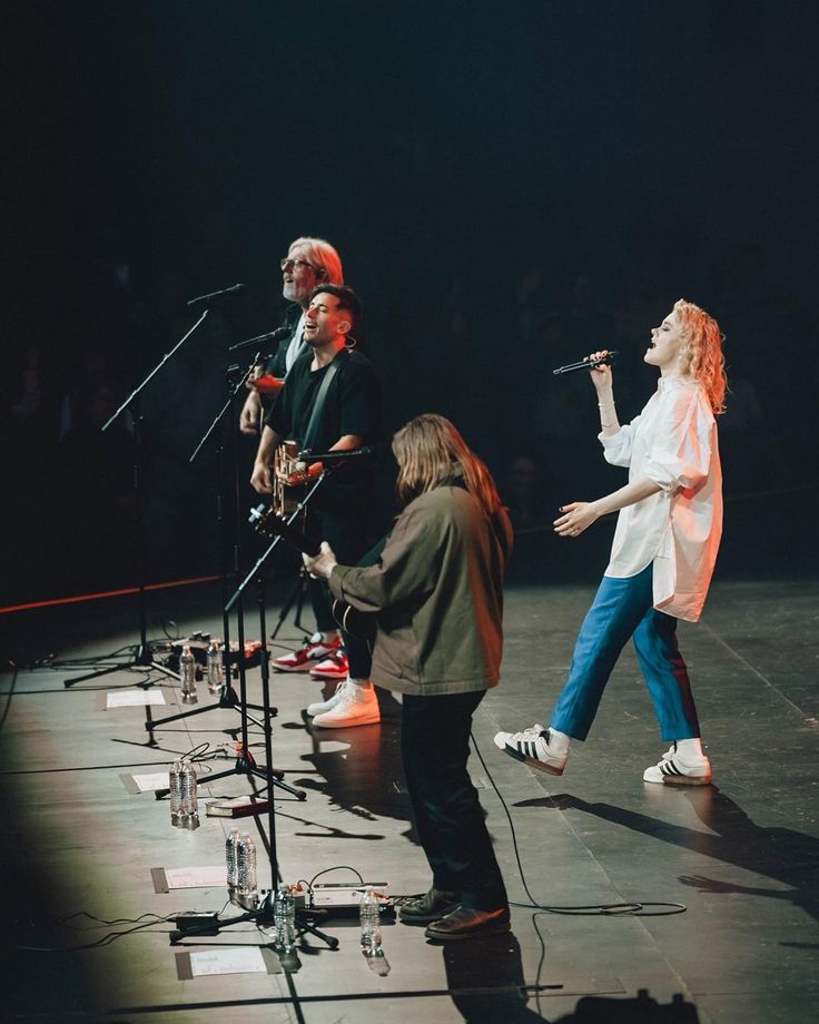 three people are singing on stage with microphones