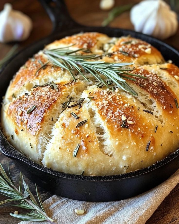 garlic bread in a cast iron skillet with rosemary sprigs on the side