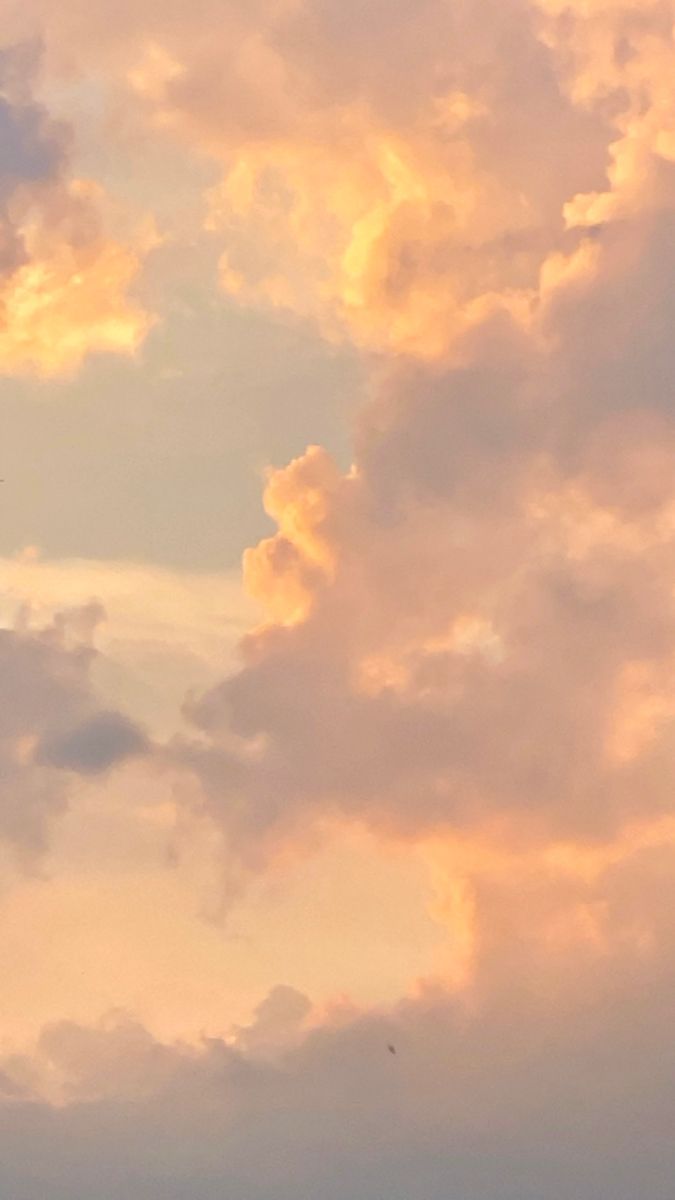 the airplane is flying high in the sky with clouds behind it and an orange glow from the sun