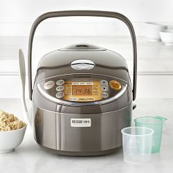 a silver rice cooker sitting on top of a counter next to bowls and cups