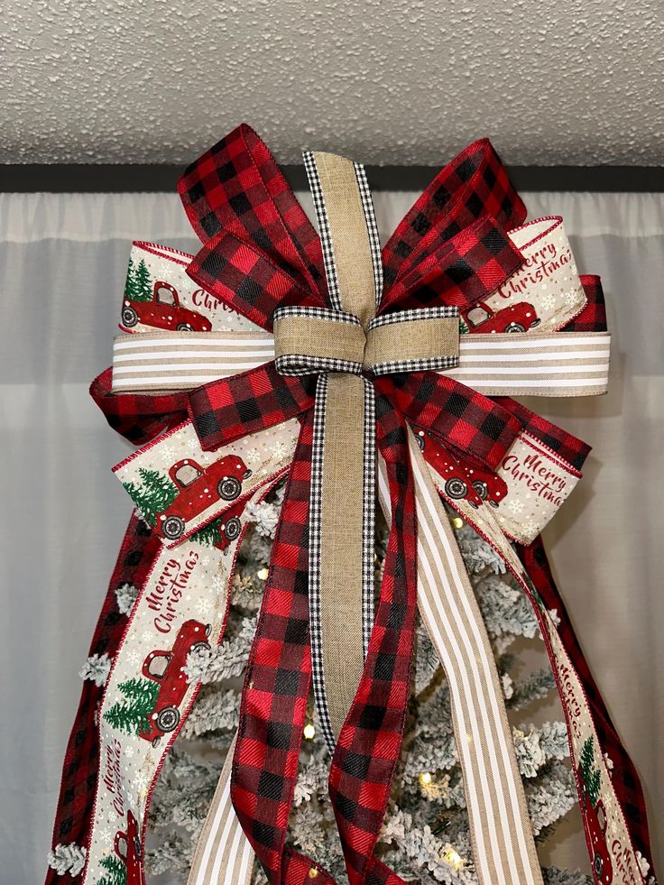 a red and white christmas tree with plaid ribbon tied around it's neck,