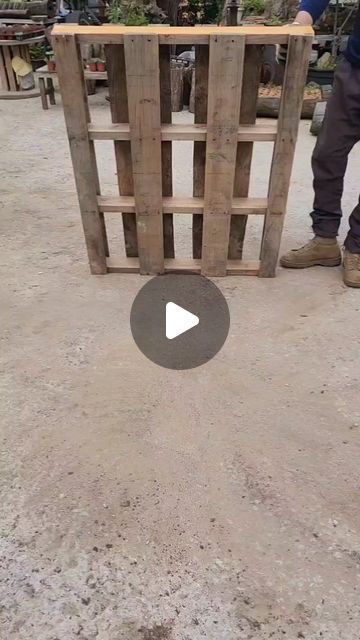 a man standing next to a wooden box on top of dirt ground with an object in front of him