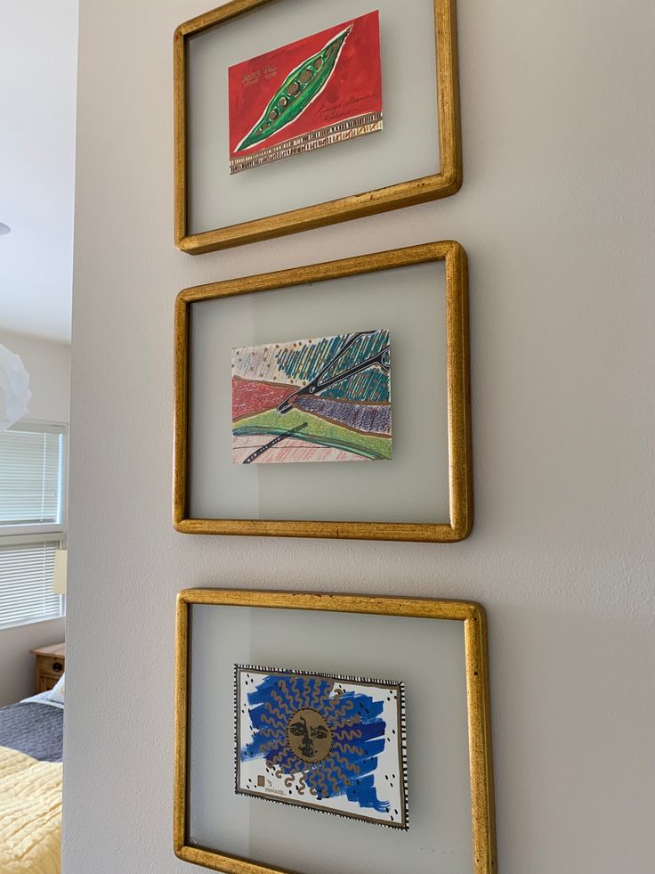 three framed pictures hang on the wall above a bed