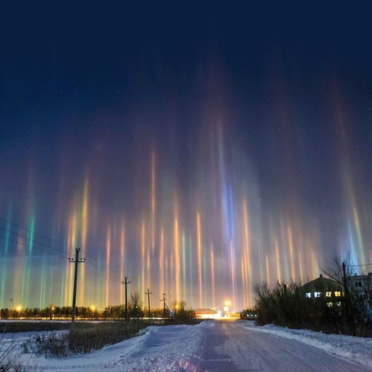 the sky is lit up with colorful lights in the distance and snow on the ground