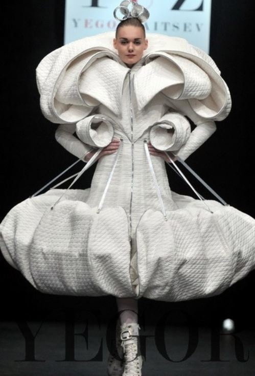 a woman is walking down the runway in a white dress with large, ruffled sleeves