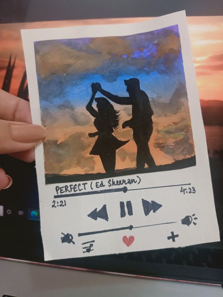 a person holding up a piece of paper with an image of two people dancing