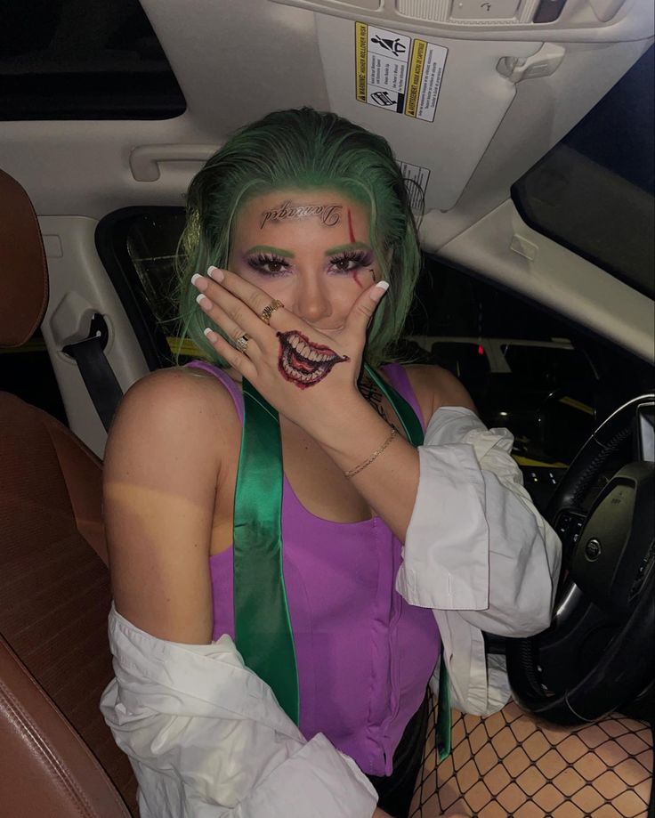 a woman with green hair and makeup sitting in a car