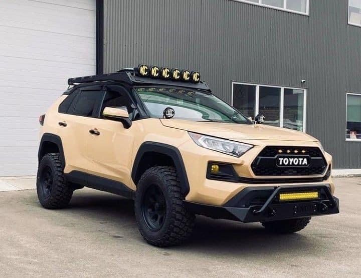 a yellow toyota truck parked in front of a building with an awning on it's roof