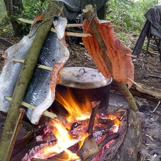 fish cooking over an open fire in the woods