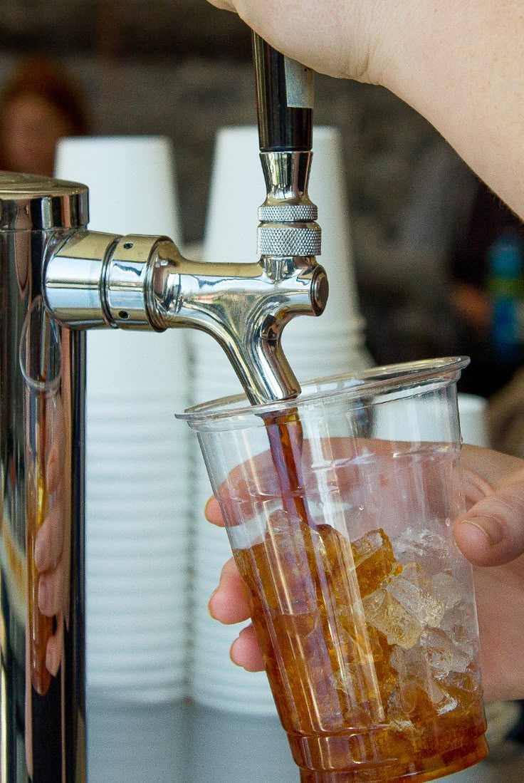 a person is filling a glass with liquid from a faucet