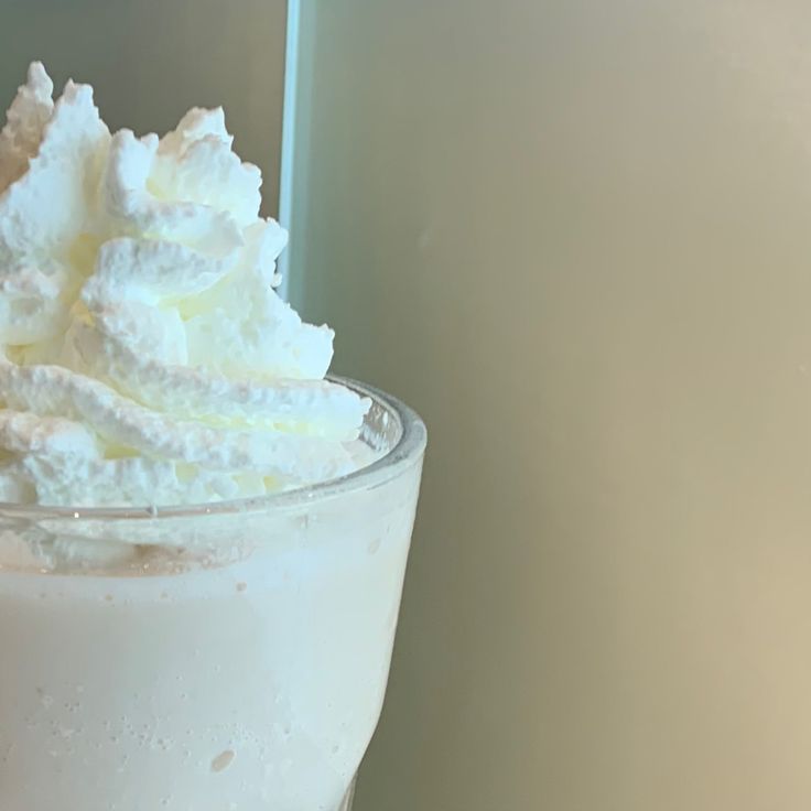 a glass filled with whipped cream on top of a table