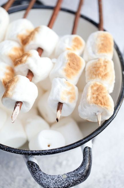 marshmallows are arranged on sticks in a bowl