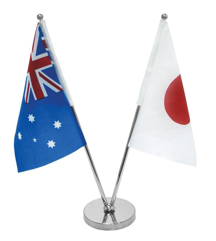 two miniature flags are placed on a metal stand with a white base and red circle at the top