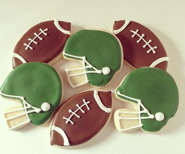 decorated cookies in the shape of footballs and helmets on a white tablecloth background