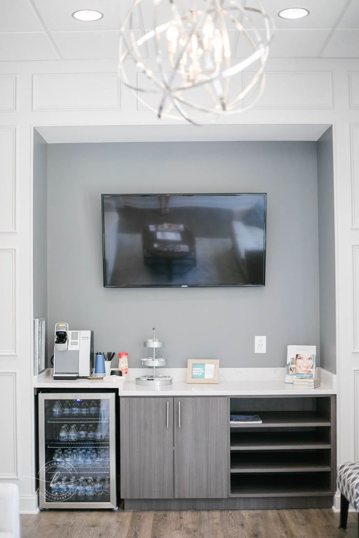 a television mounted to the wall above a wine cooler