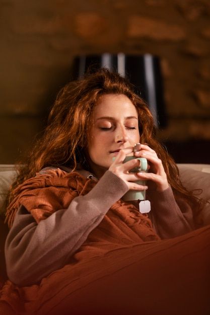 a woman sitting on a couch with her eyes closed and holding a bottle in her hand