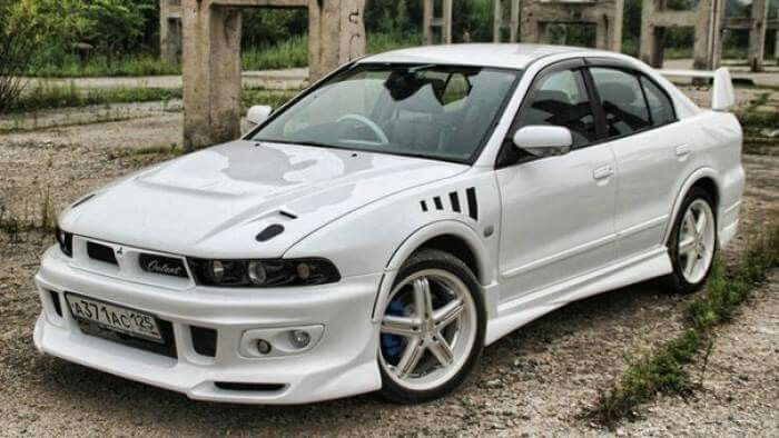 a white sports car parked on the side of a road next to some trees and bushes