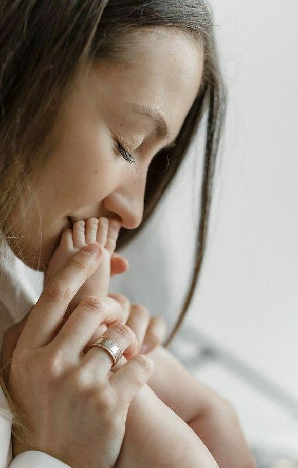 a woman is holding her hand to her chest and looking down at the ground while wearing a ring