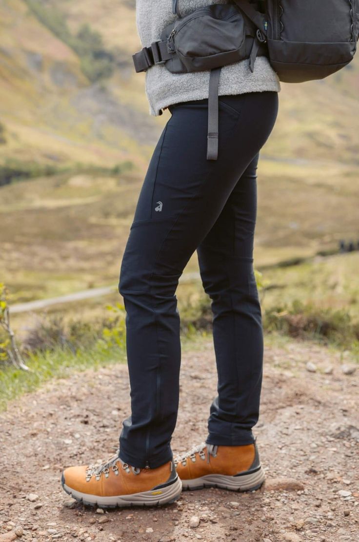 a person standing on a dirt road with a backpack over their shoulder and one foot in the air