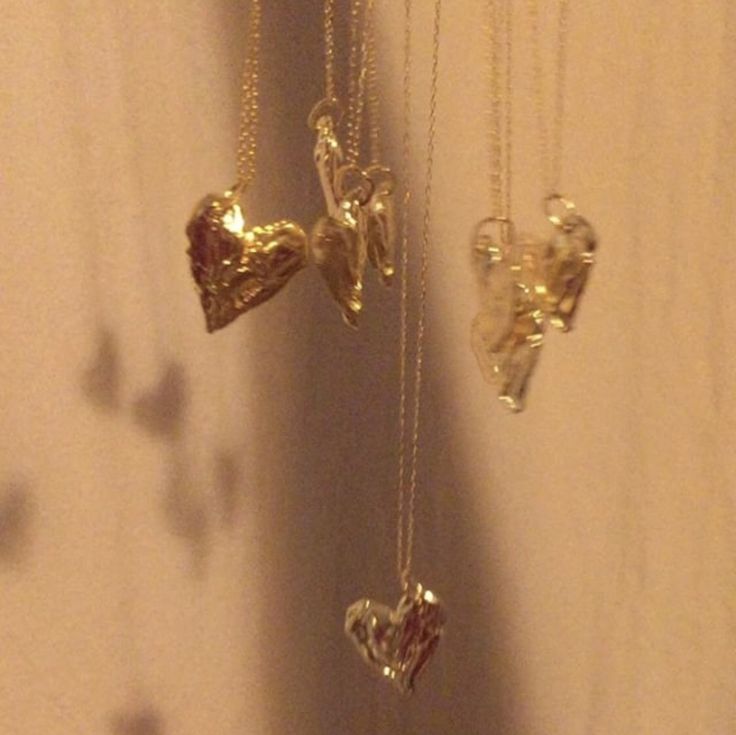 three pieces of gold are hanging on a wall next to each other in the shape of hearts