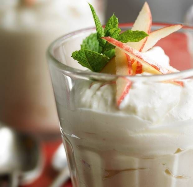 two glasses filled with ice cream and fruit on the top one is topped with whipped cream