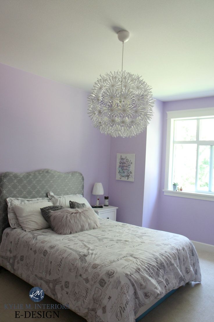 a bed sitting in a bedroom next to a window with a chandelier hanging from the ceiling