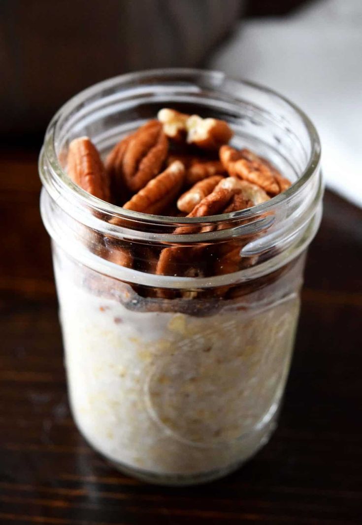 a jar filled with oatmeal and nuts on top of a wooden table