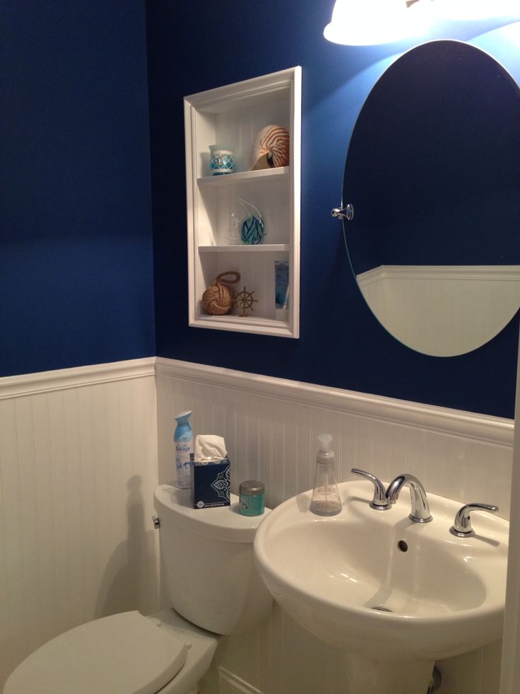 a white toilet sitting next to a sink in a bathroom under a blue wall mounted mirror