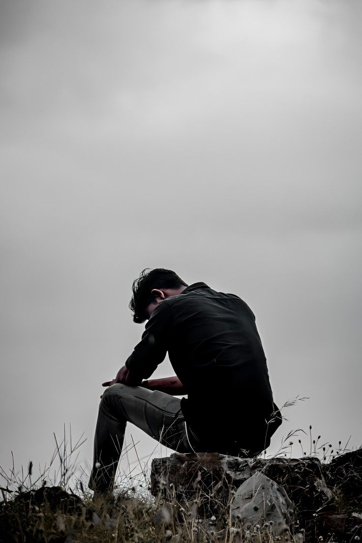 a man sitting on top of a rocky hill