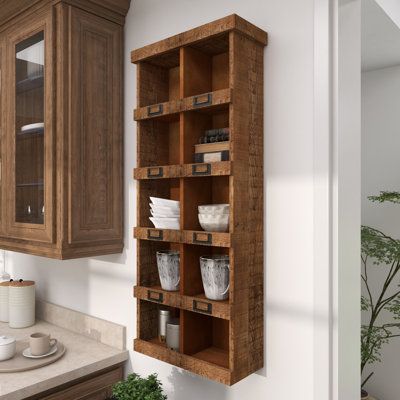 a kitchen with wooden cabinets and dishes on the shelf above the sink, next to a potted plant