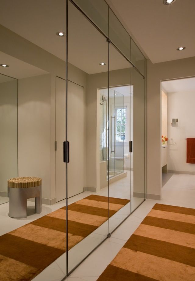 a large mirror in the middle of a room next to a bench and rug on the floor