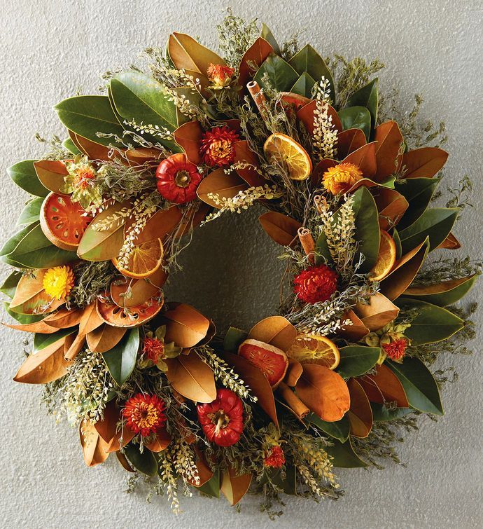 a wreath is hanging on the wall with flowers and leaves around it's edges