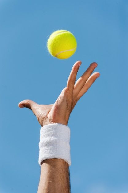 a tennis ball being thrown into the air by a person's hand with a bandage on it