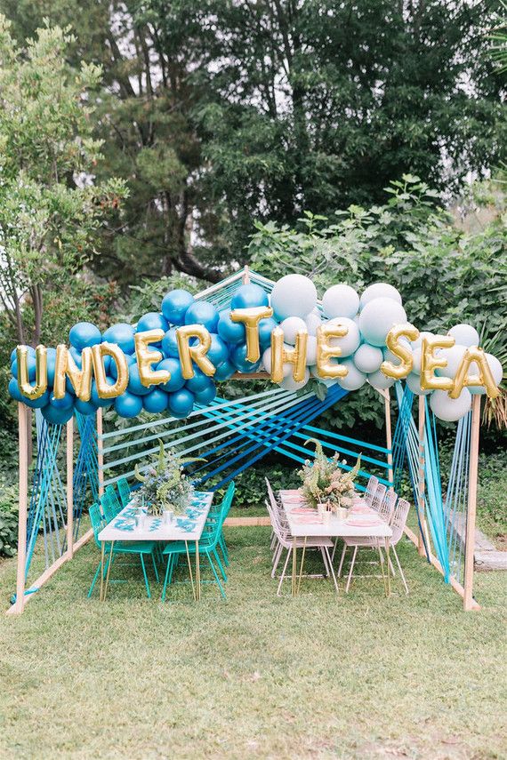 an under the sea party with blue and white balloons, table set up for two