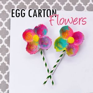 an egg carton with flowers painted on it and candy sticks sticking out of the top