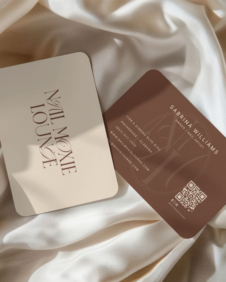 a white and brown business card sitting on top of a bed covered in silks