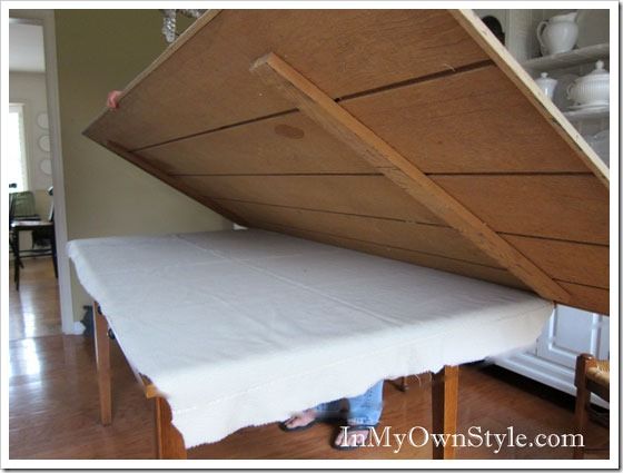 a person standing under a bed with a wooden frame and mattress on it's side