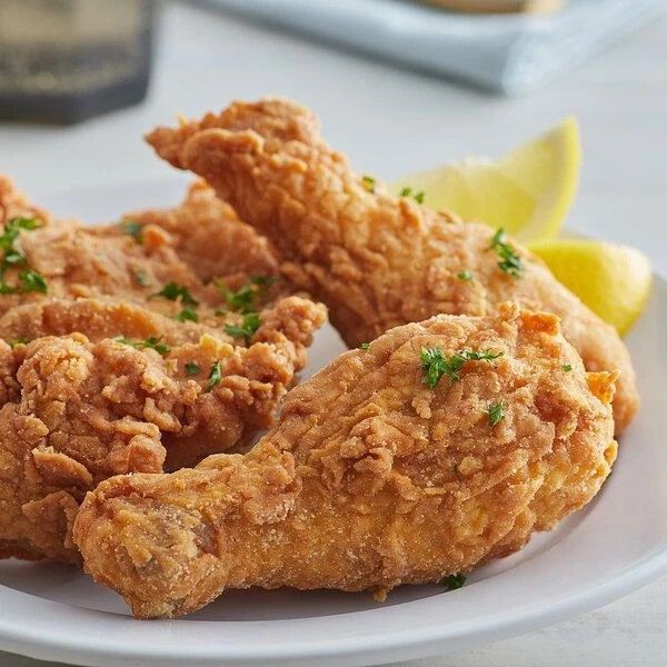 fried chicken on a white plate with lemon wedges