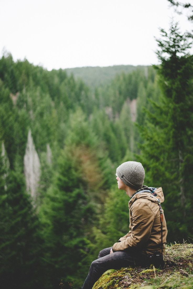 a person sitting on top of a hill with trees in the background and text overlay