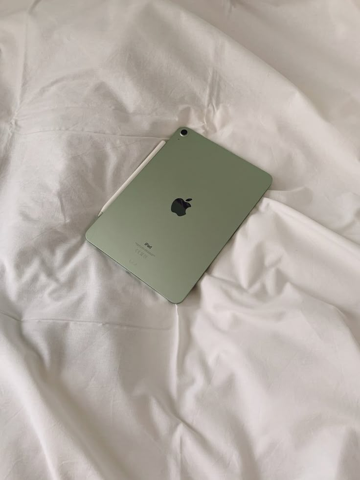 an apple ipad sitting on top of a white bed sheet in the middle of it's frame