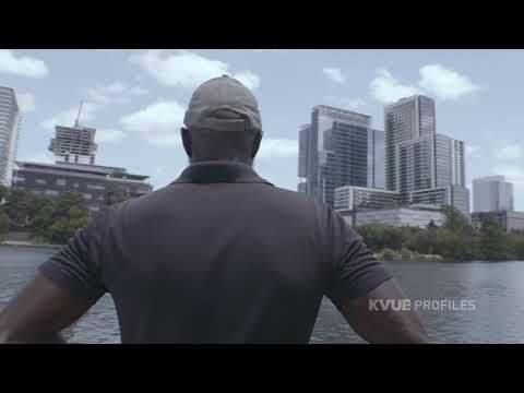 a man standing on the edge of a body of water in front of tall buildings